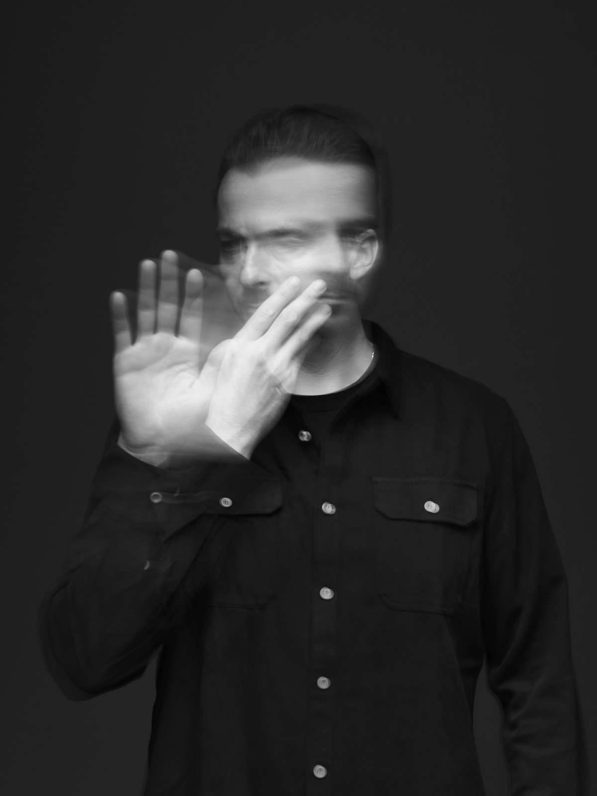 P. Willem, hand raised in front of his face, captured in motion blur against a dark backdrop