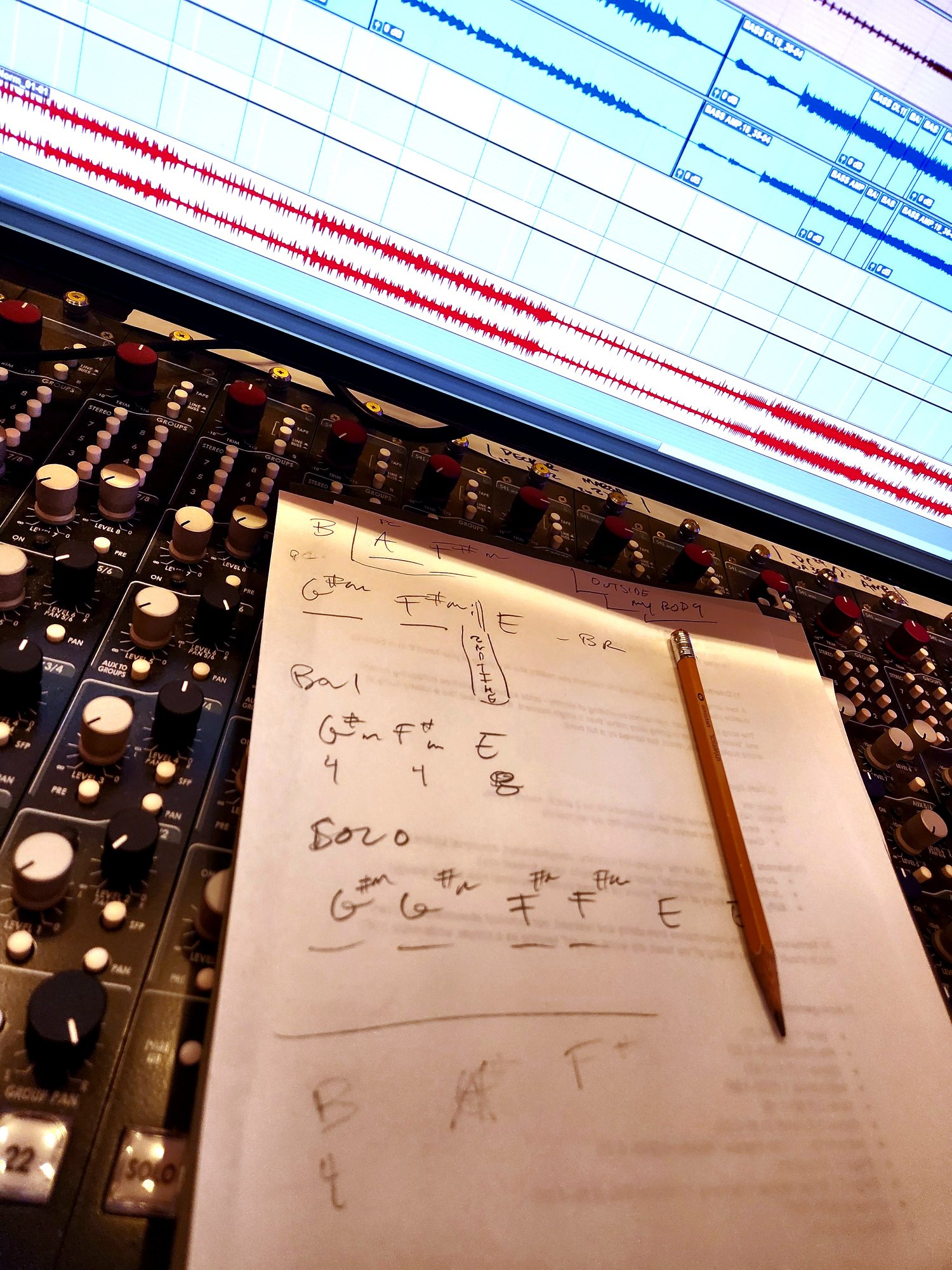 Handwritten chord chart on mixing console at Rare Signals with Pro Tools waveforms in background